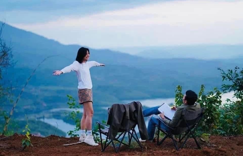 Hai người ngồi trên đồi đất đỏ nhìn ra hồ Tà Đùng